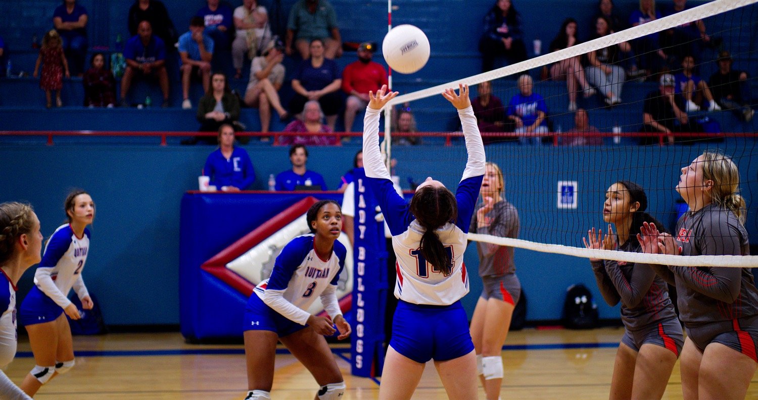 Quitman setter Peyton Kruckner floats the ball as (left to right) Kaylie Wood, Kallie Hoover and Allie Berry anticipate spiking it, while Mineola defenders Olivia Hughes, Kyra Jackson and Jocelyn Whitehead stand ready at the net. [view more volleyball shots]
